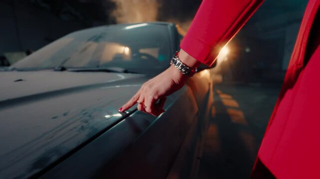 unrecognizable woman in a red coat runs her finger over an old retro dusty car, unlocks it with a key and sits in the driver's seat. Concept of a female ghost rider.