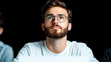Fototapeta premium Young Man with Glasses Deep in Thought Against a Dark Background