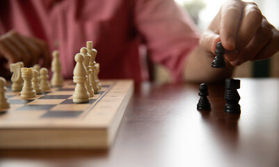 A hand moves a black pawn on a chessboard, surrounded by other black pieces. The image showcases a...