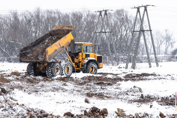Dump or truck at a building site in winter season. Powerful modern equipment for earthworks....