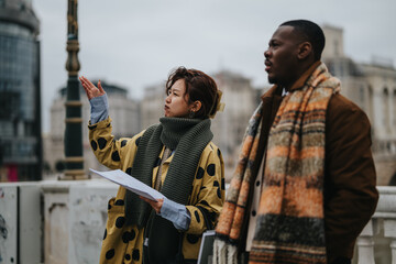 Two individuals on a city street engage in a thoughtful conversation, analyzing notes and their surroundings. They are dressed warmly, suggesting a chilly day, with urban architecture as the backdrop.