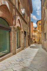 Fototapeta premium Old street in the historical center of Siena, the UNESCO World Heritage Centre unchanged for 13-14 centuries, with its medieval streets looked like in the early Middle Ages. Italy, 2019 
