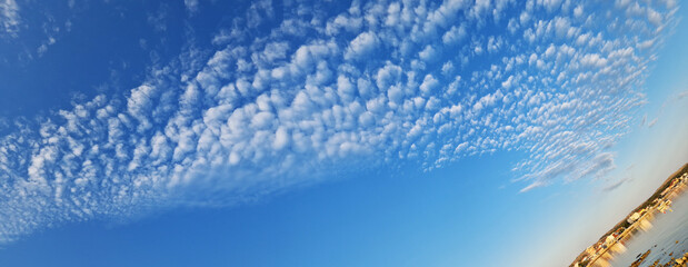 Scenic coastal town with rippled cloud formations over calm sea at sunset
