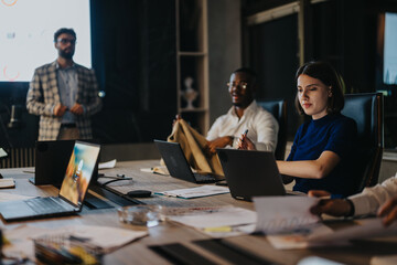 A diverse team of people engages in a collaborative meeting in a modern office environment. They...
