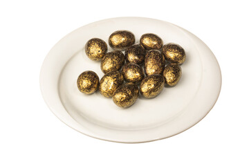 Generated imageGold color dragee in white plate isolated on a white background. Close up shot. Ramadan candy concept idea