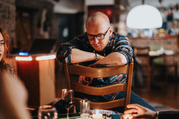 A contemplative man sits in a warm room, leaning on a chair surrounded by dim lights and candles, creating a cozy and intimate atmosphere.