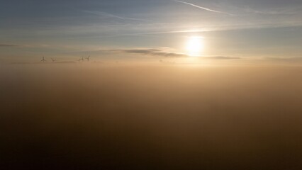Ethereal Sunrise Over Dense Morning Fog with Wind Turbines