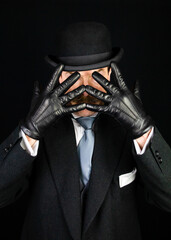 Gentleman in Dark Formal Suit and Bowler Hat and Leather Gloves Held in Front of Face. Vintage Style and Retro Fashion.
