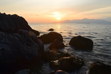 Sunset coastal rocks, ocean waves, distant mountains, peaceful scene