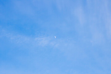 The bright moon is clearly visible in the clear blue sky today
