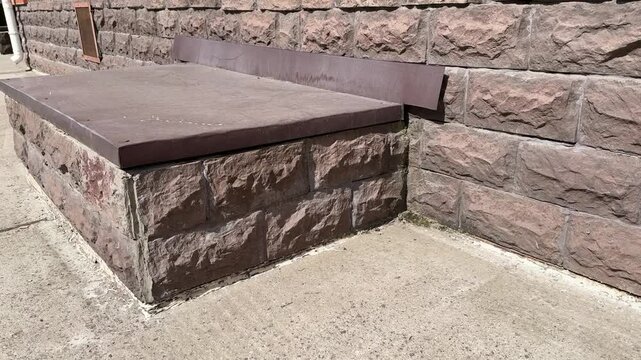Basement entrance in the building of house has window is located below ground level. Window is covered with galvanized steel in brown color sheet to protect basement from precipitation during rain