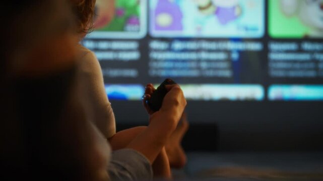 A child sits close to an adult, both focused on a projector displaying colorful animated films. The cozy living room is illuminated softly, creating a warm atmosphere for movie night