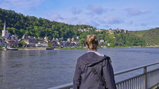 Following woman walking on a riverside pathway looking at beautiful view of the Rhine River Valley, Sankt Goar, Germany