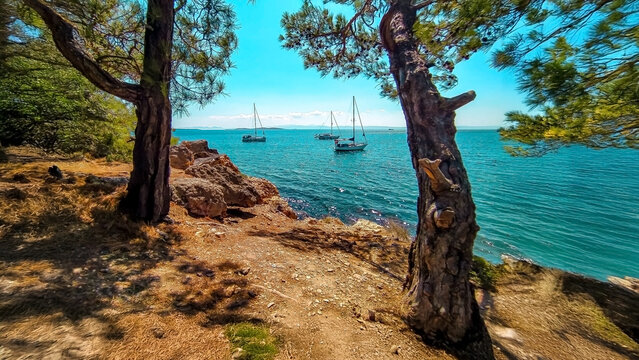 Scenic summer view of the turquoise sea, sailboats, and rocky coastline Edremit
