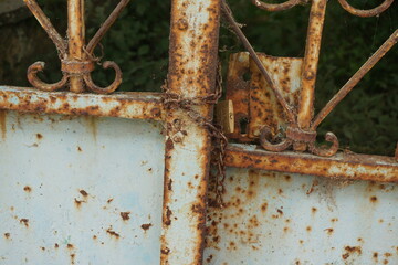 Old rusty door with chains and padlock full of cobwebs of a uninhabited and abandoned house