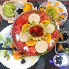 A vibrant fruit platter with guavas, oranges, strawberries, watermelon, and grapes, arranged...