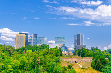 Fototapeta premium Luxembourg City aerial panoramic view of Kirchberg central business district with skyscraper buildings and Three Acorns Park with green trees, Luxembourg cityscape skyline horizon with blue sky