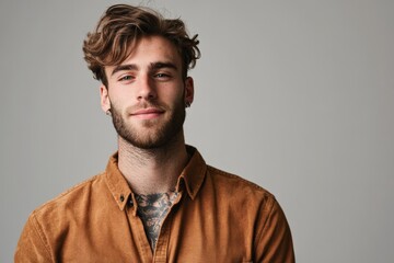 Fototapeta premium Confident Young Man with Stylish Hair and Casual Attire Posing Against a Neutral Background