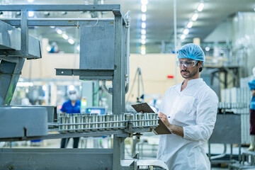 Engineer supervising the food production process in a high tech manufacturing plant inspecting...