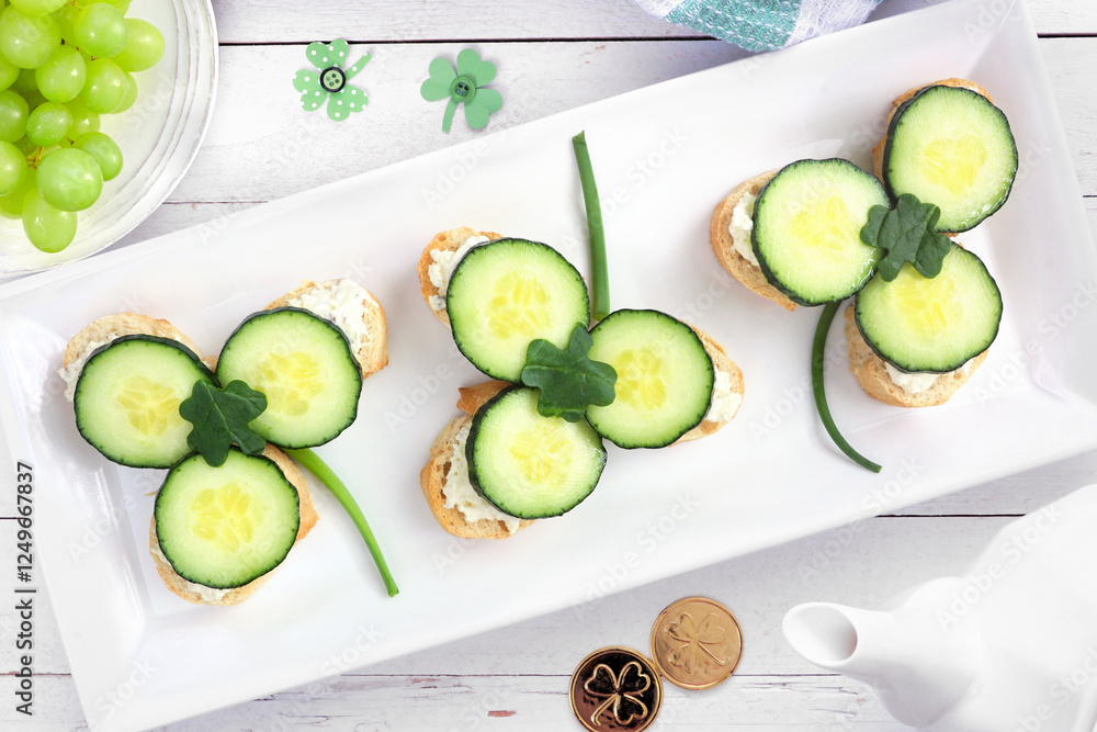 Poster st patricks day shamrock open tea sandwiches with cream cheese and cucumber. top view table scene ov
