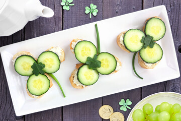 St Patricks Day shamrock open tea sandwiches with cream cheese and cucumber. Above view table scene...