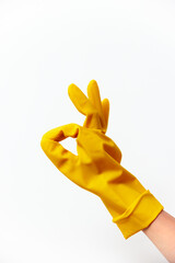 Hand in yellow rubber glove making an okay sign on white background