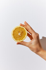Person holding half an orange on white surface with other half in their hand