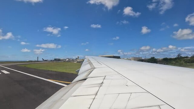 Large airplane taxiing on the runway at Mauritius airport. View from the window above the wing.