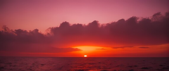 Obraz premium A stunning red sunset casting a warm glow over peaceful sea waters where the horizon produces hues of pink and orange that captivate the senses