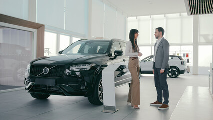 People standing inside of car dealership and having conversation. Talking about required...