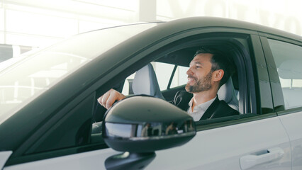 Very close camera view of handsome Caucasian male sitting at drivers seat of new car. Man in...