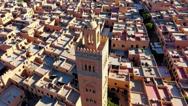 Explore the vibrant rooftops of Marrakech filled with traditional architecture and bustling life. The historic Koutoubia Mosque stands tall amidst the colorful homes under a clear sky.