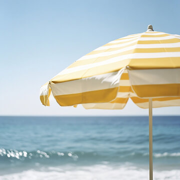 A parasol with white and yellow stripes, close-up, blurred sea in the background, during the day,