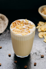 Creamy latte with whipped foam, dried apple slices, and cinnamon, served on a dark textured surface