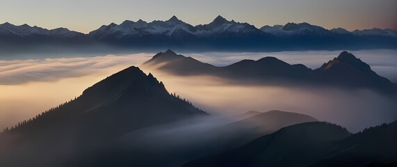 A dramatic image of thick mist hovering over mountains at dawn where the peaks shimmer faintly through shrouded layers of mystery