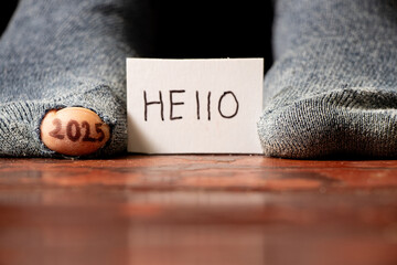 2025 written on the toe and the toe sticking out of the hole of the torn sock and the text on the...