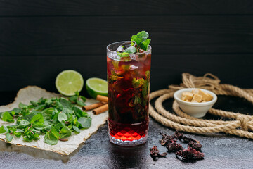 Refreshing hibiscus cocktail with lime, mint, and ice in a tall glass, summer and tropical vibes