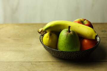 Still life of fresh fruits in a bowl on wooden table, selective focus