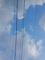Obraz premium Electrical Cables Crossing a Cloudy Blue Sky