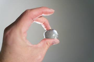 Hand Holding a Diamond on Grey Background