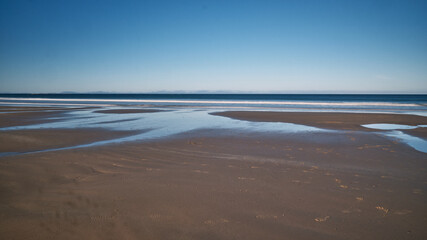 The image captures a serene, ethereal seascape bathed in a soft, dreamy light. Smooth, flowing waves gently undulate across the frame.