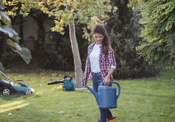 Woman working in garden, carrying watering can for plants irrigation © Budimir Jevtic