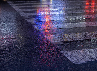 Urban nightlife glows as reflections dance on wet pavement after a refreshing rain shower in a...