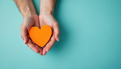 Hands hold orange heart on blue background. Symbol of community support, volunteer appreciation. Gesture of kindness, gratitude. Simple image ideal for social media print. Image perfect for