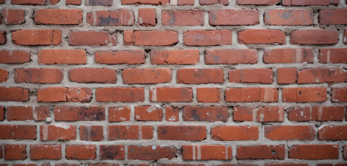 Fototapeta premium Red brick wall with aged mortar and rough surface, industrial building exterior texture with rustic appeal, weathered building facade, architectural surface, urban industrial wall design.