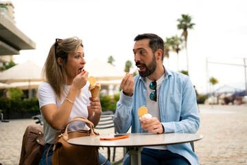 a smiling couple sharing an ice cream, sitting at a table in a cafe
