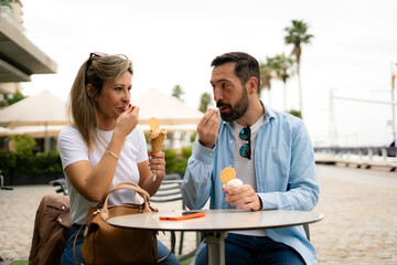 a smiling couple sharing an ice cream, sitting at a table in a cafe