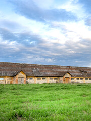 Large, old building with a lot of windows sits in a grassy field