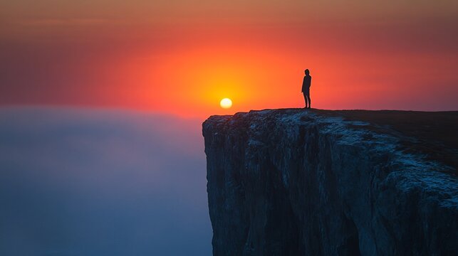 Capture essence of renewal with a minimalist image of a solitary figure standing on the edge of a cliff silhouetted against the first light of dawn embracing the promise of a new year - Powered by Adobe