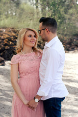 Obraz premium Couple in love walking on the beach, happy pair on beach, photo of the young family, woman in long pink dress and man outdoors, lovely couple, people in love, engagement photography